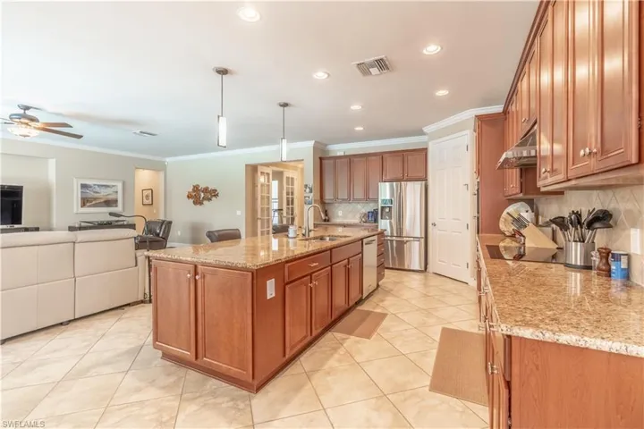 Kitchen with stainless steel fridge with ice dispenser, tasteful backsplash, a kitchen island with sink, and ceiling fan