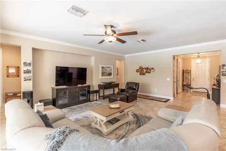 Tiled living room featuring ornamental molding and ceiling fan