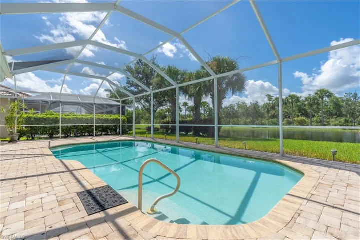View of swimming pool with glass enclosure and a patio area