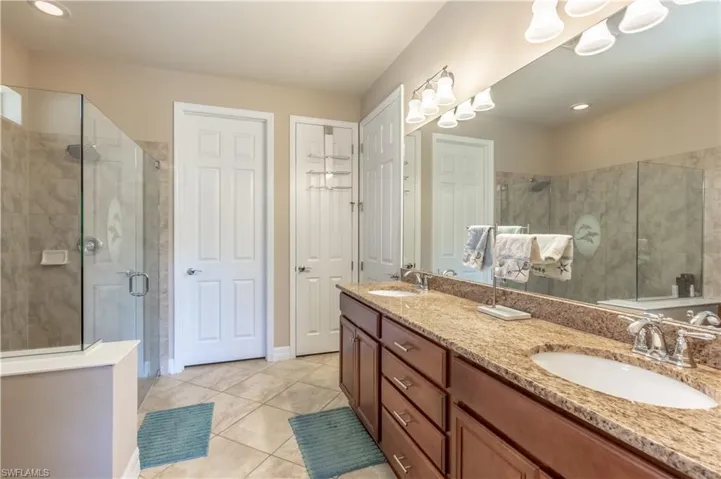 Bathroom with a shower with door, tile patterned flooring, and dual bowl vanity