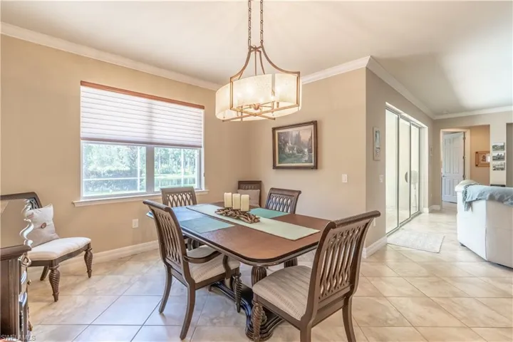 Tiled dining area with an inviting chandelier and crown molding