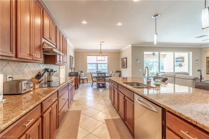 Kitchen with hanging light fixtures, light tile patterned floors, decorative backsplash, dishwasher, and black electric stovetop