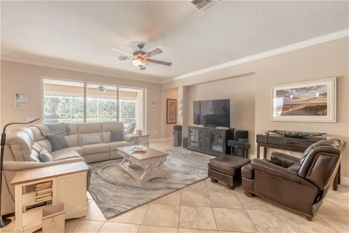 Living room featuring crown molding, light tile patterned floors, and ceiling fan