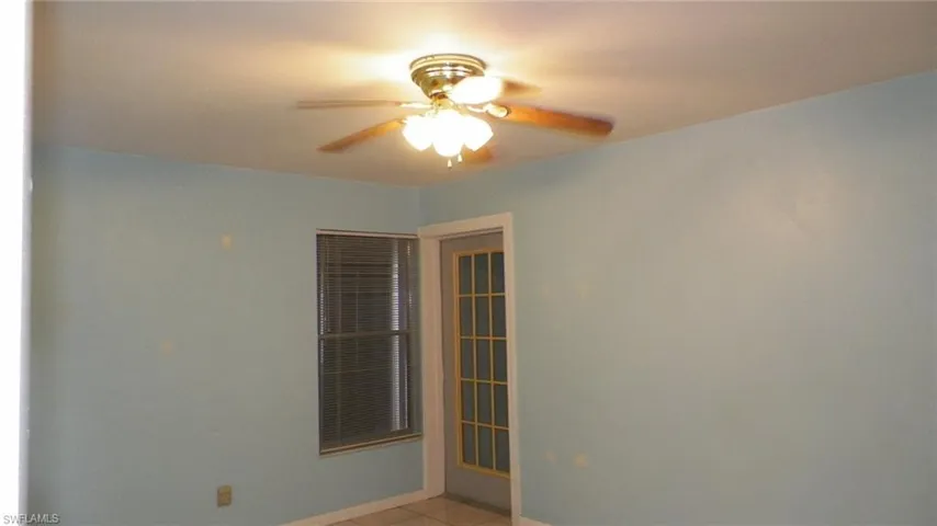 Ceiling fan with light fixture, window with blinds, and a glass-paneled door
