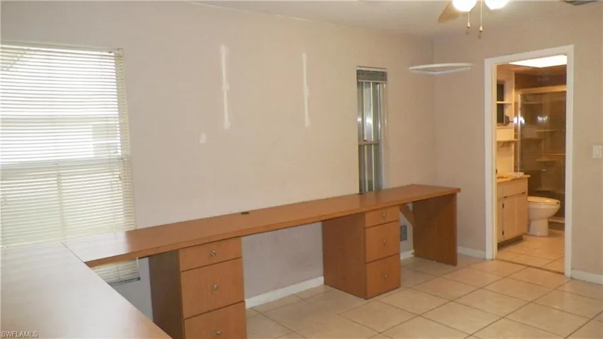 Room featuring tile flooring and built-in wood-finish desks with drawer storage