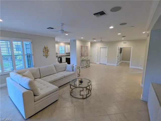 Living room featuring crown molding, recessed lighting, ceiling fan, and light tile patterned flooring