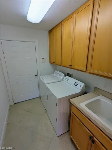 Laundry room with independent washer and dryer, cabinet space, and light tile patterned floors