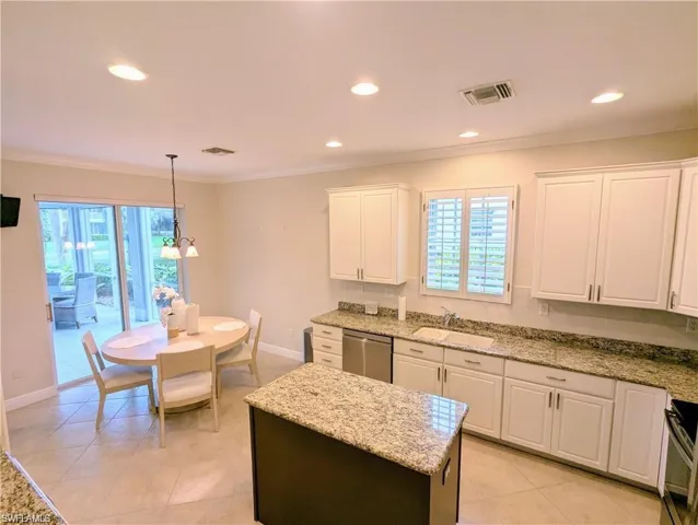 Kitchen featuring white cabinets, light stone countertops, recessed lighting, a kitchen island, and crown molding