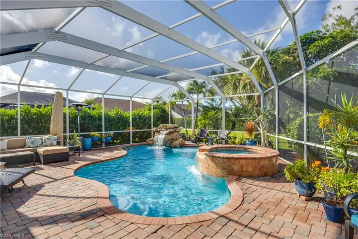 View of swimming pool featuring a patio, a pool with connected hot tub, and glass enclosure