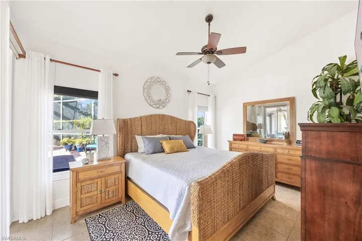 Bedroom with multiple windows, light tile patterned floors, lofted ceiling, and a ceiling fan