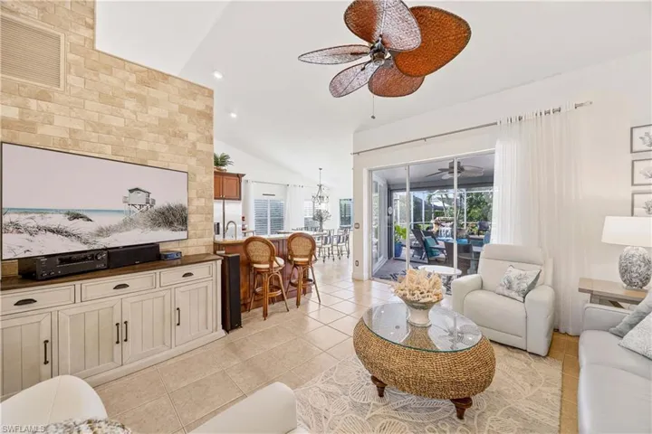 Living room featuring vaulted ceiling, a ceiling fan, light tile patterned flooring, and recessed lighting