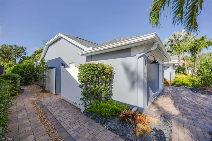 View of property exterior with stucco siding, a garage, and a gate