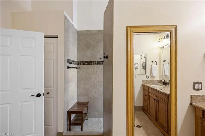 Full bath with vanity, a walk in shower, and tile patterned floors