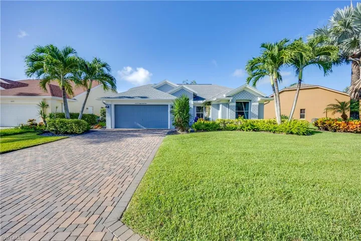 Ranch-style home featuring an attached garage, decorative driveway, a front lawn, and stucco siding