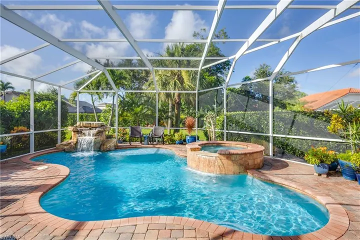 View of pool with a pool with connected hot tub, a patio area, and a lanai