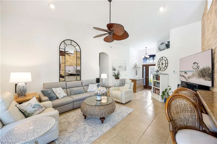 Living area with ceiling fan, a towering ceiling, light tile patterned floors, arched walkways, and recessed lighting