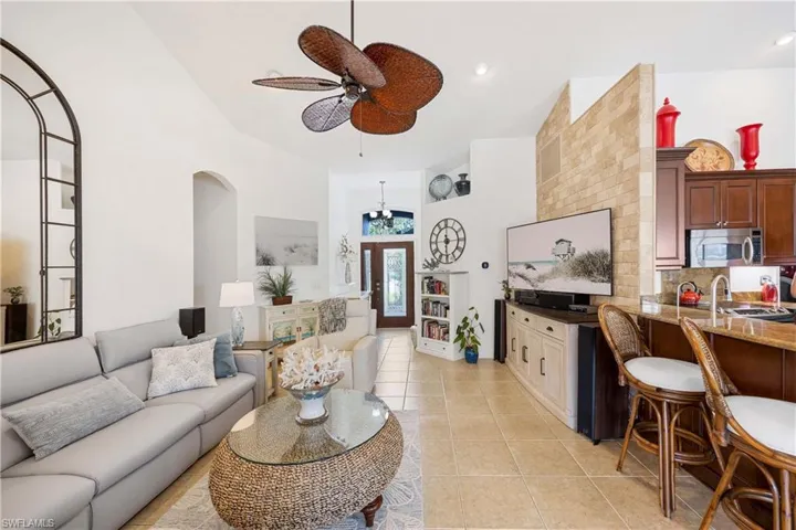 Living room with ceiling fan, light tile patterned floors, and a high ceiling
