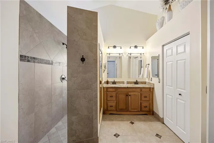 Bathroom with double vanity, walk in shower, and tile patterned flooring