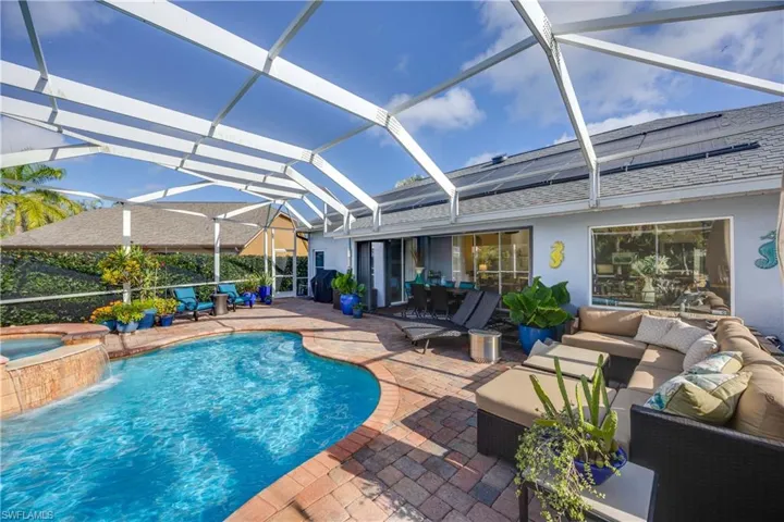 View of pool featuring an outdoor living space, a patio, a pool with connected hot tub, and glass enclosure