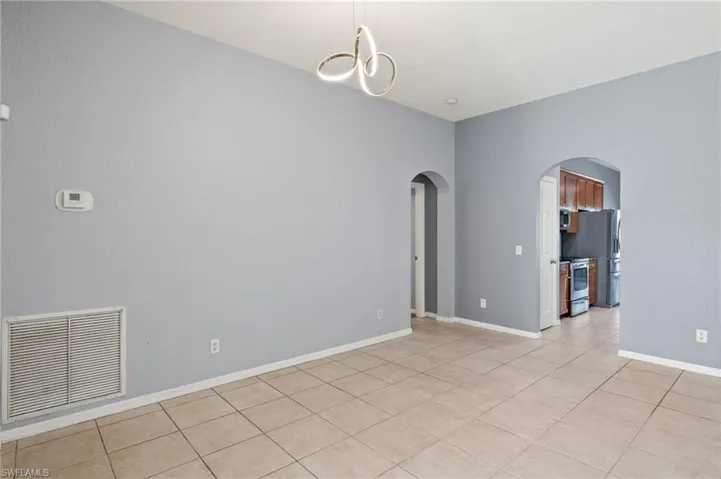 Unfurnished room featuring arched walkways, light tile patterned flooring, and a chandelier