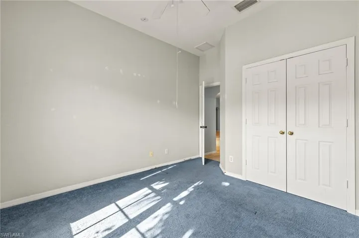 bedroom featuring dark carpet, a closet, and ceiling fan