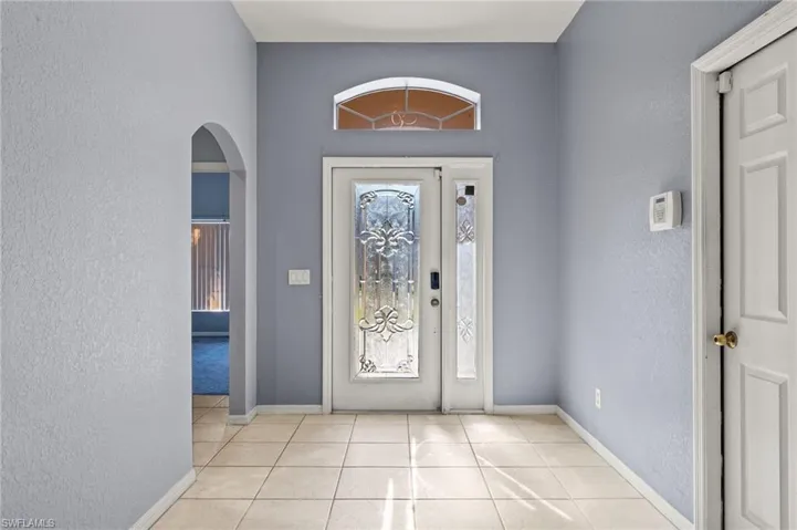 Foyer entrance featuring tile patterned flooring, a textured wall, and arched walkways