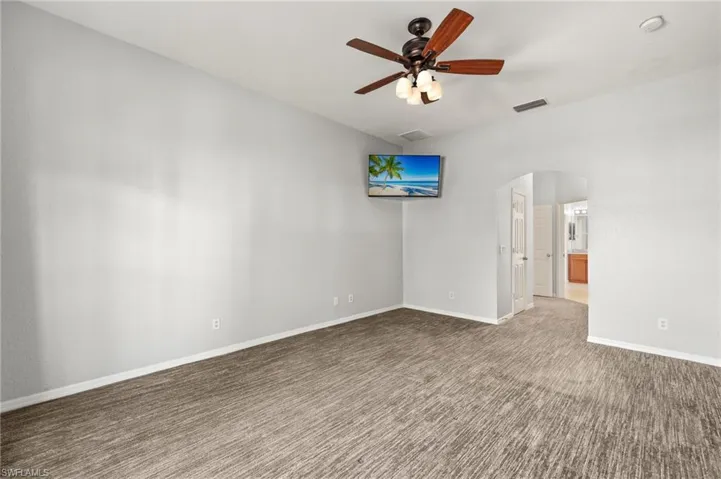 Unfurnished room featuring arched walkways, carpet, and ceiling fan