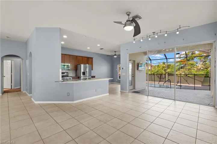 Unfurnished living room with a ceiling fan, arched walkways, light tile patterned flooring, and recessed lighting