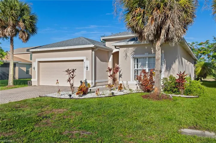 Ranch-style house featuring stucco siding, a garage, driveway, and a front lawn