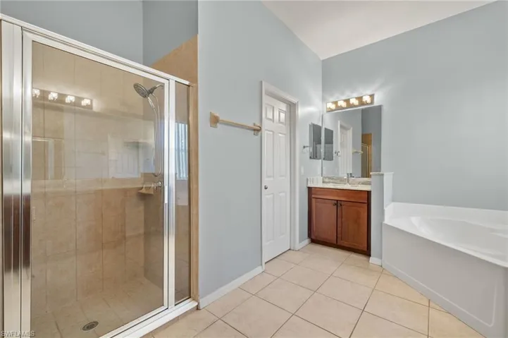 Full bathroom featuring vanity, a stall shower, tile patterned flooring, and a garden tub
