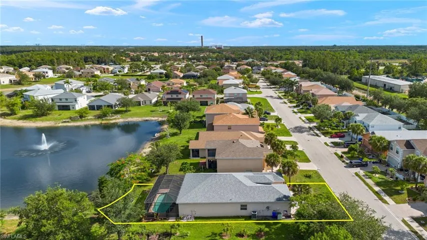Aerial perspective of suburban area with property parcel outlined and a nearby body of water