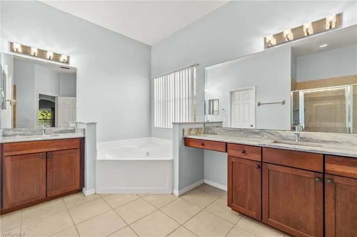 Full bath with a shower stall, a garden tub, two vanities, and tile patterned floors