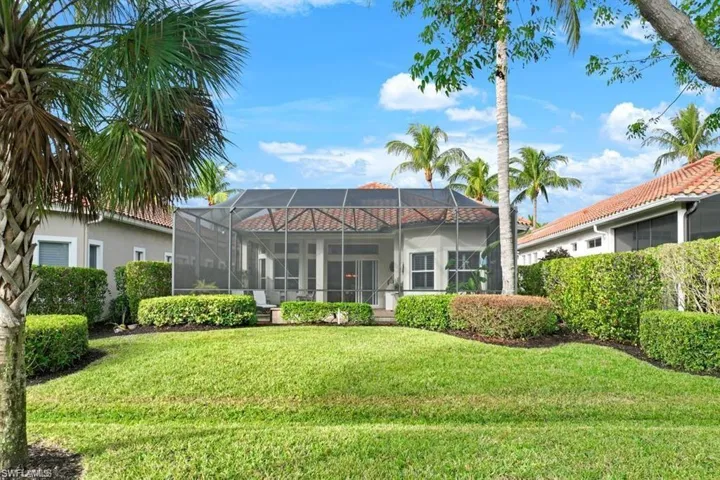 Rear view of property featuring glass enclosure, a sunroom, a lawn, and stucco siding