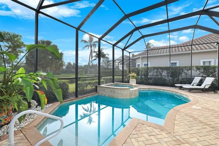 View of swimming pool with a sunroom, glass enclosure, a pool with connected hot tub, and a patio area