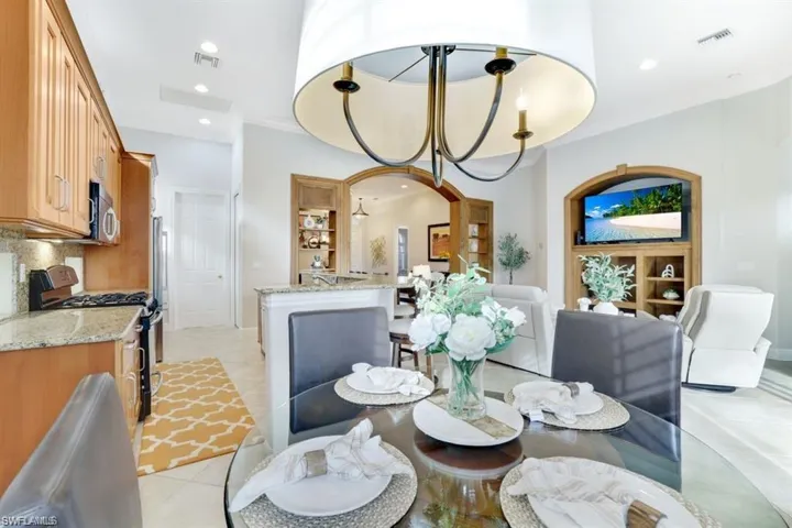 Dining room featuring recessed lighting, light tile patterned floors, arched walkways, ornamental molding, and a chandelier