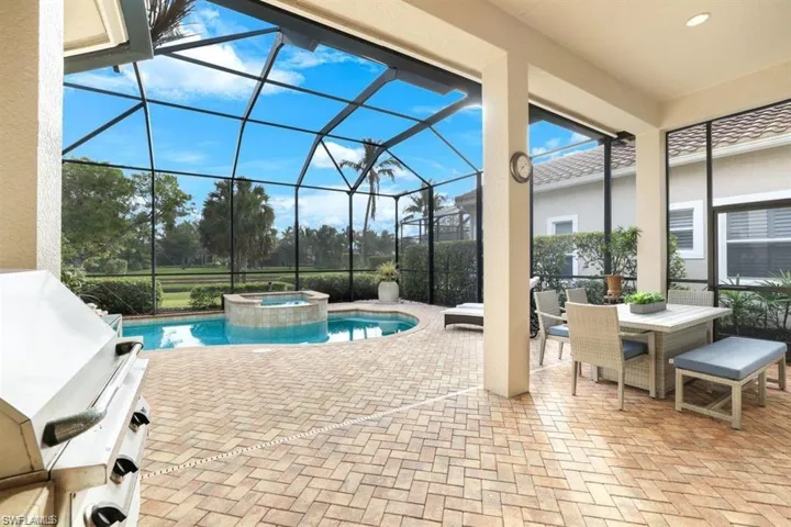 View of pool with a patio area, glass enclosure, a sunroom, and a pool with connected hot tub