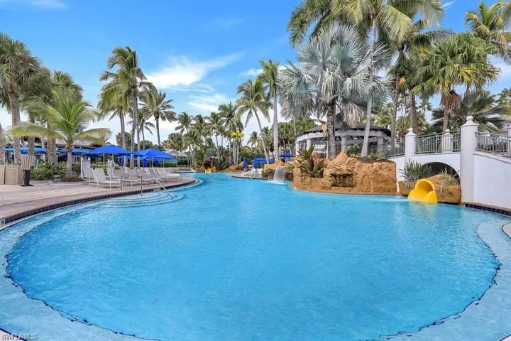Community pool with a water slide and a patio