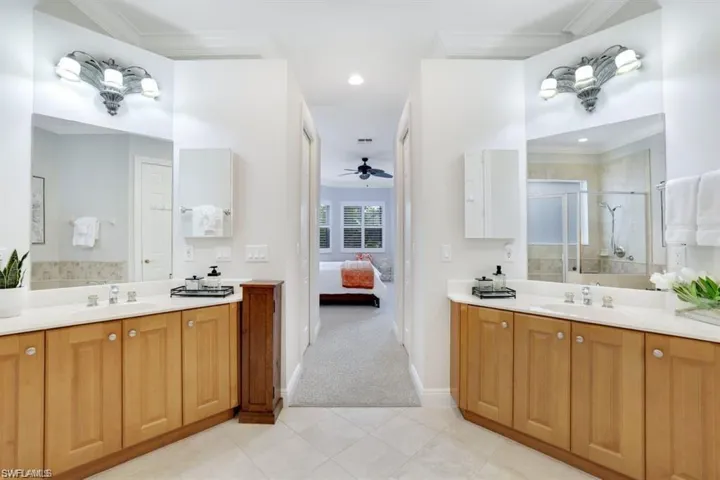 Full bathroom with crown molding, a stall shower, two vanities, ensuite bathroom, and a ceiling fan