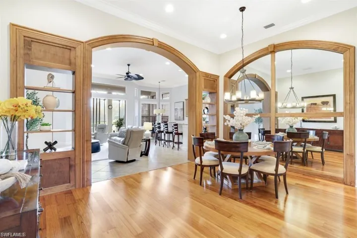 Dining space with light wood-type flooring, ceiling fan, a chandelier, arched walkways, and recessed lighting