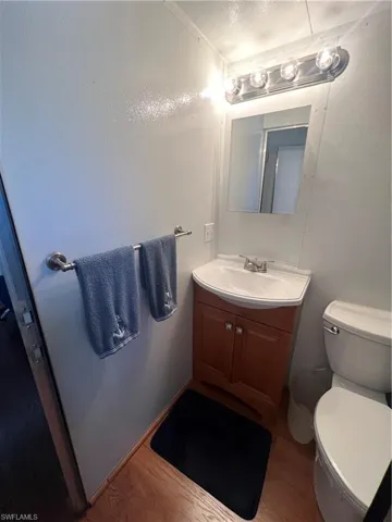 Half Bath with Wood Cabinetry and Closet Area