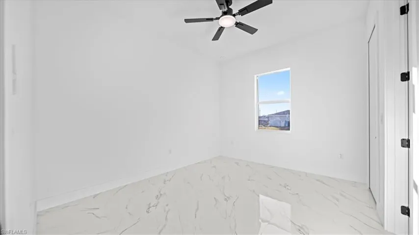 Spare room featuring ceiling fan and light marble finish floors