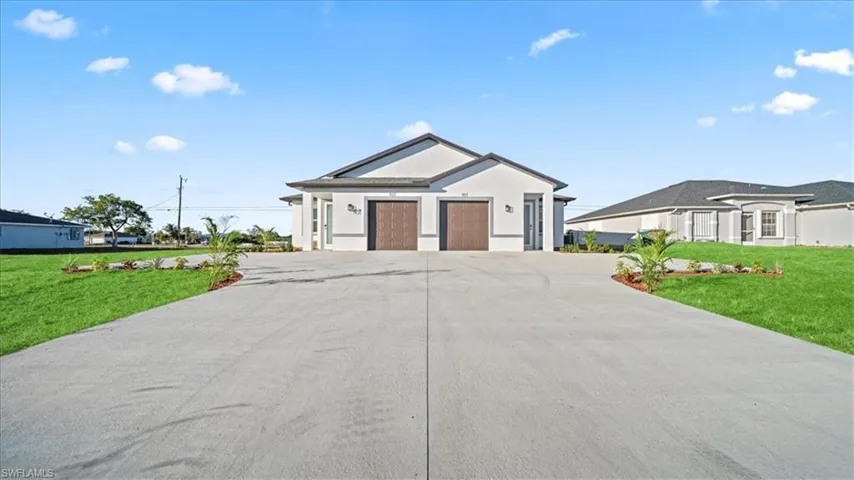 View of front facade featuring a front lawn, concrete driveway, and stucco siding