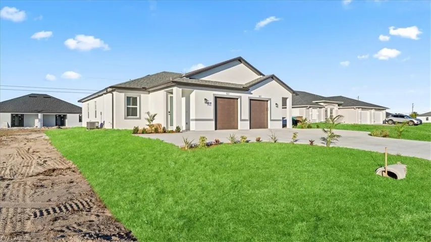 View of front facade featuring an attached garage, driveway, a front yard, and stucco siding