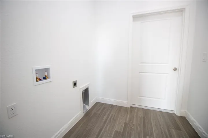 Clothes washing area with hookup for a washing machine, dark vinyl-style floors, and electric dryer hookup