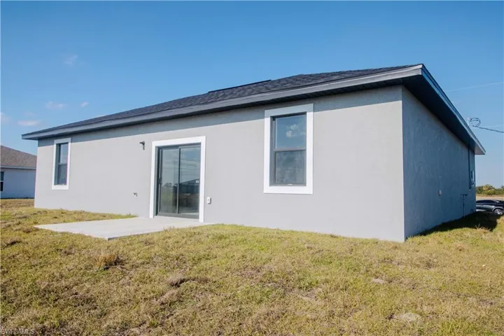 Back of house featuring a lawn and a patio
