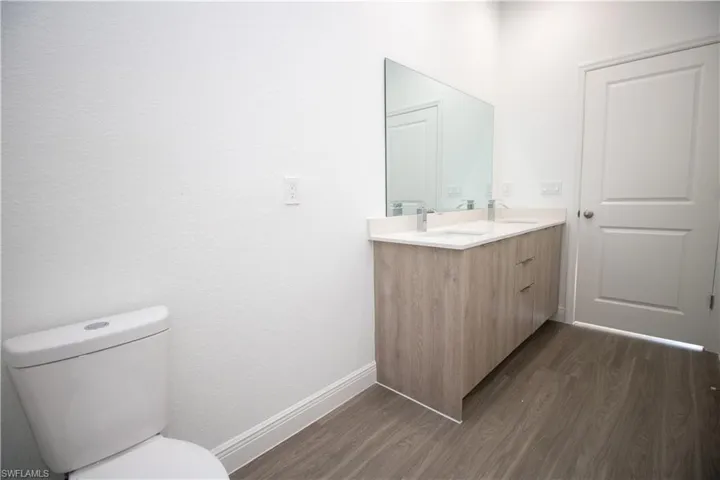 Master Bathroom with vinyl-style floors, toilet, and vanity