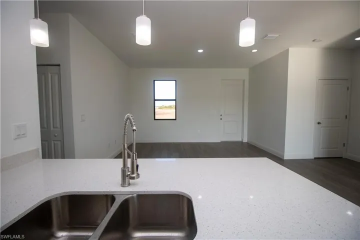 Kitchen featuring sink, light brown cabinets, appliances with stainless steel finishes, and hanging light fixtures