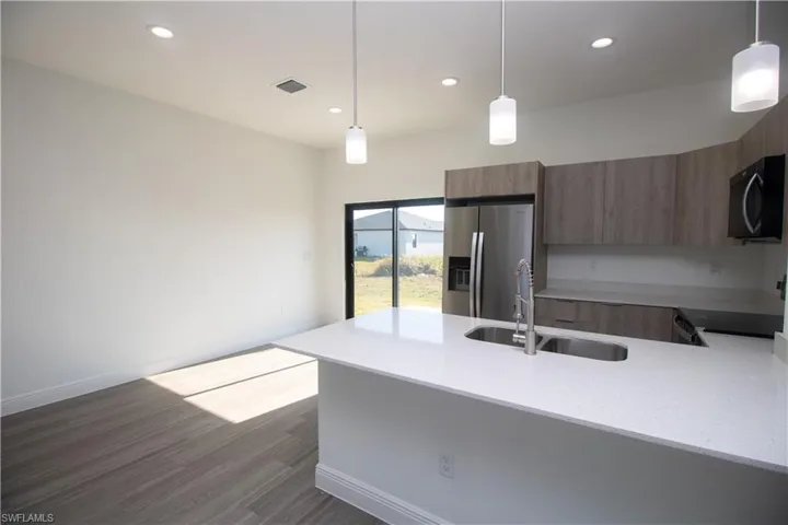 Kitchen featuring sink, light brown cabinets, appliances with stainless steel finishes, and hanging light fixtures