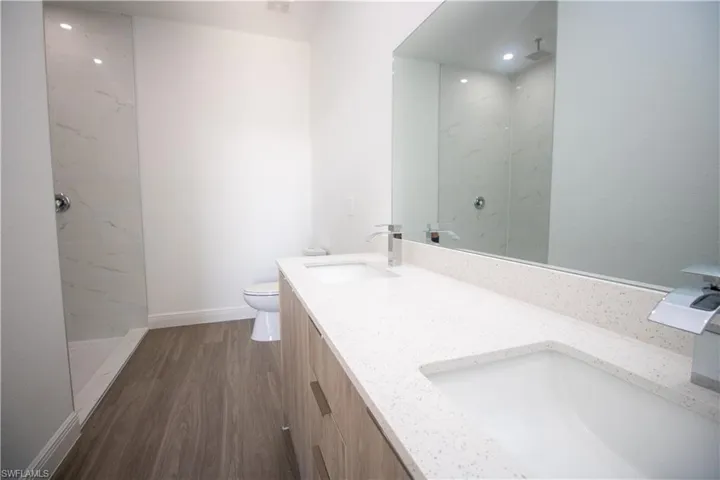 Master Bathroom featuring toilet, vanity, a tile shower, and vinyl-style floors