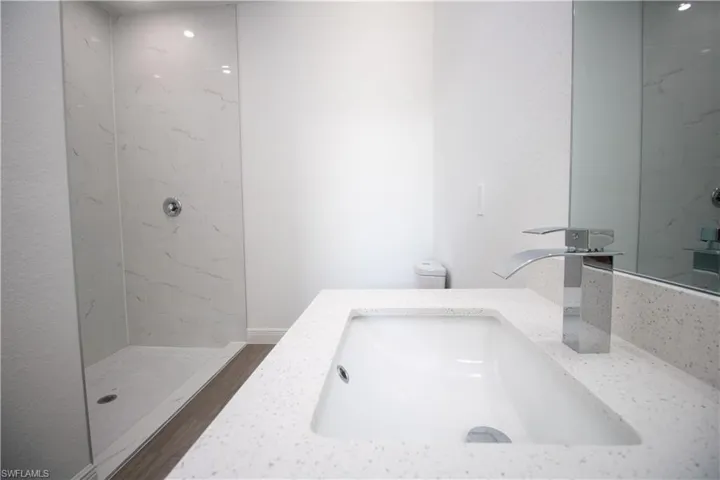 Master Bathroom featuring vinyl-style flooring, tiled shower, vanity, and toilet